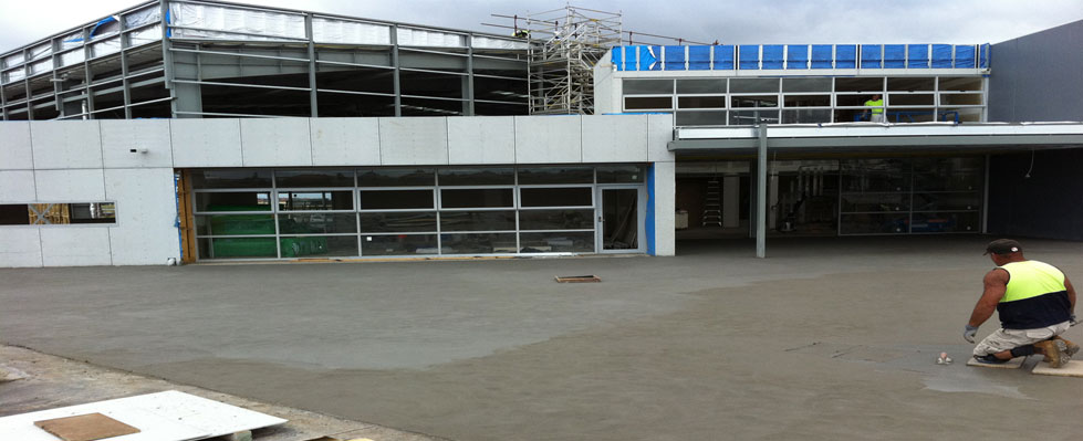 Lazzaro concreter hand-finishing a large concrete surface in front of a commercial building